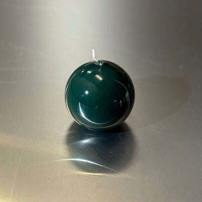 Green spherical object on a reflective surface