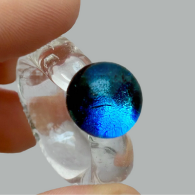 Clear glass pipe with a blue glass bowl held by a hand against a gray background