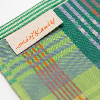 Close-up of a green plaid fabric with a brand label on a white background