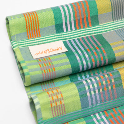 Folded fabric with green, orange, and blue plaid pattern on a white background
