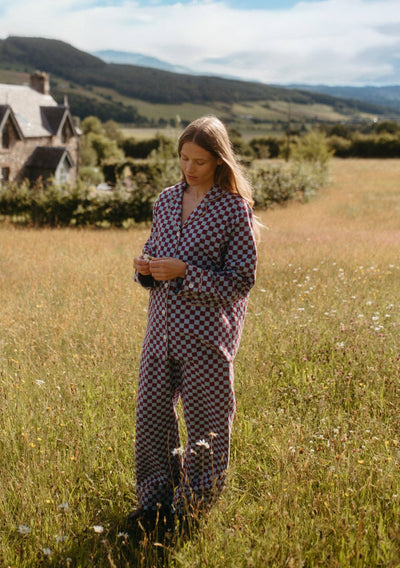 Woman in a checkered outfit standing in a field with a scenic background