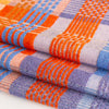 multicoloured tea towel. mix of flat weave and terry cloth, in red, blue, orange and yellow yarns. folded and stacked, close up