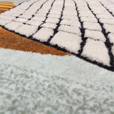close up of Take the Grip - Captivating Tufted Wool Carpet by Trine Krüger | Gradient Mint to Green with Striking Orange Hues | Black and White Grid Pattern | Non-Rectangular Organic Shape | Iconic Modern Art for Contemporary Living Spaces