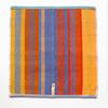 multicoloured tea towel. mix of flat weave and terry cloth, in red, blue, orange and yellow yarns. the back of the tea towel is shown flat from above with the hanger and label visible at the bottom