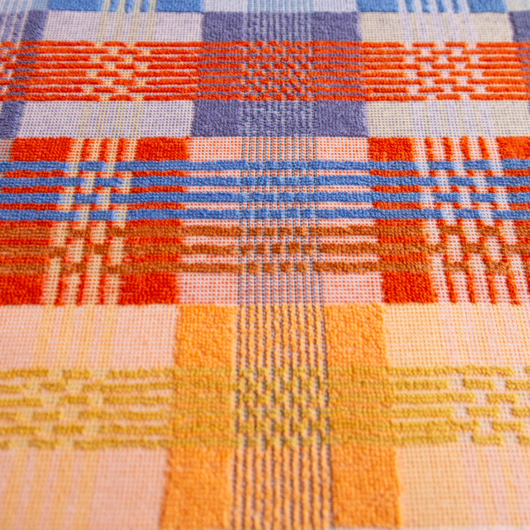 multicoloured tea towel. mix of flat weave and terry cloth, in red, blue, orange and yellow yarns. a close up of the design