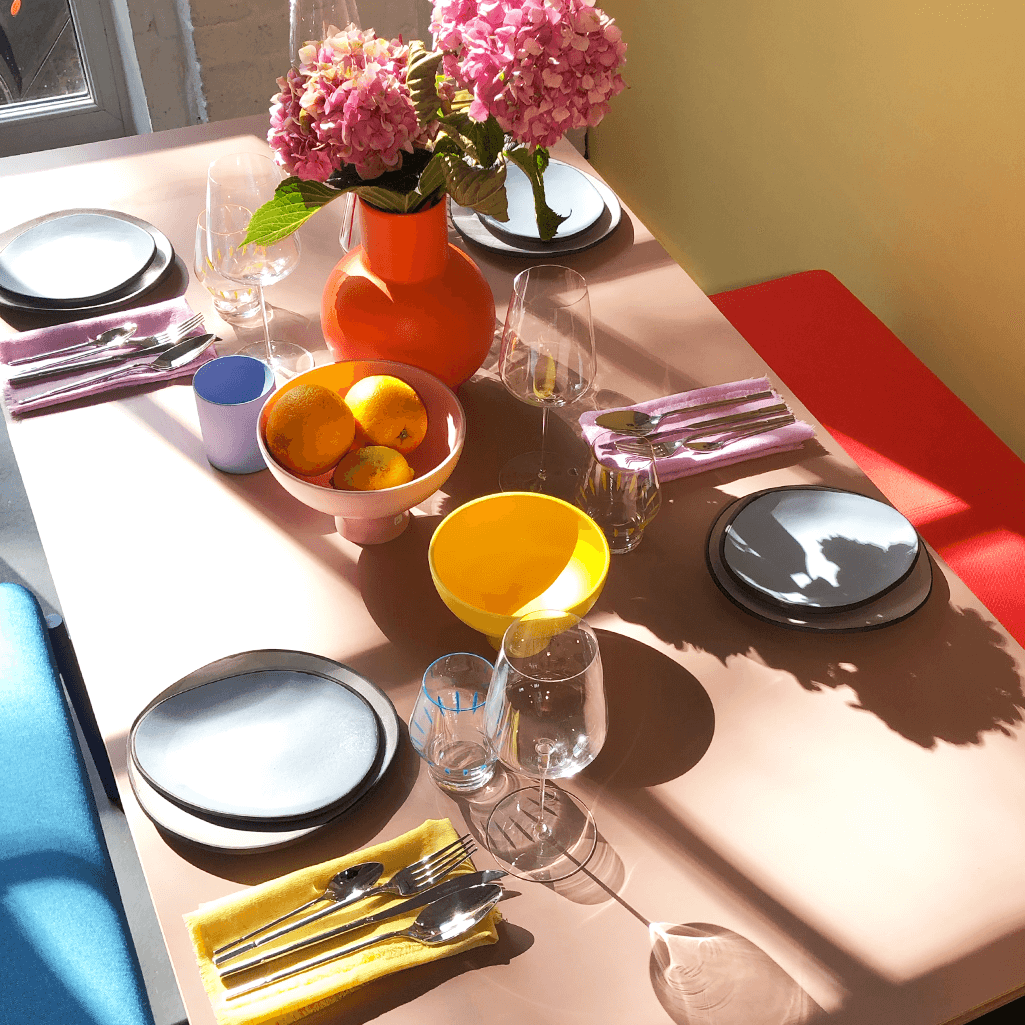 stainless Steel 16 piece cutlery, shiny "Allegro" cutlery, made by Herdmar in Portugal, set on a table with summery colours and pastel plates and napkins