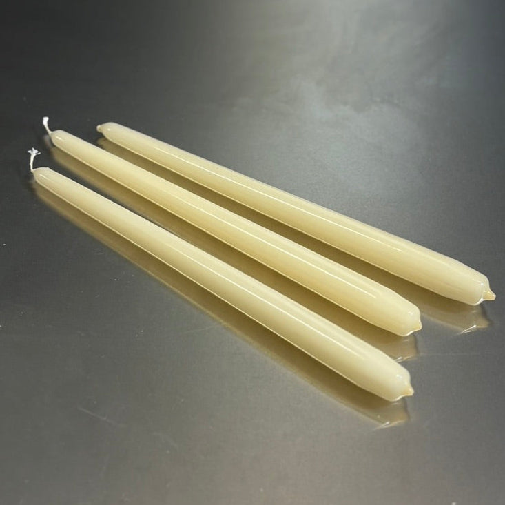 three white candles on a reflective gray surface