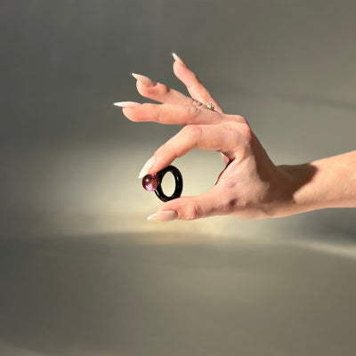 Hand holding a black and red object against a neutral background