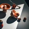 Collection of ceramic tops and bowls on a reflective surface with shadows.