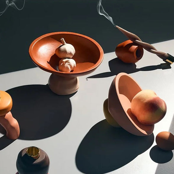 Collection of ceramic tops and bowls on a reflective surface with shadows.