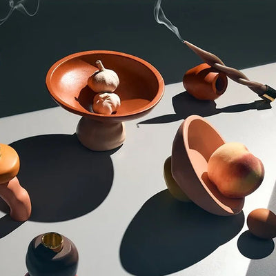 Collection of ceramic tops and bowls on a reflective surface with shadows.