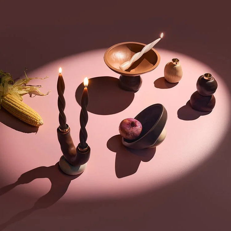 Table setting with corn, candles, and ceramic items on a pink surface