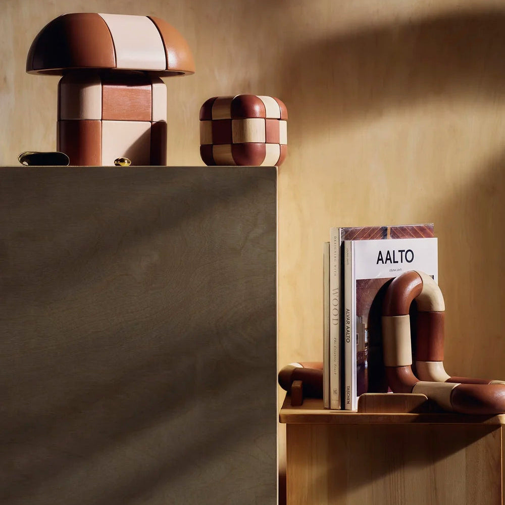 Decorative mushroom-shaped objects on a shelf with a book titled 'Aalto' against a textured wall.