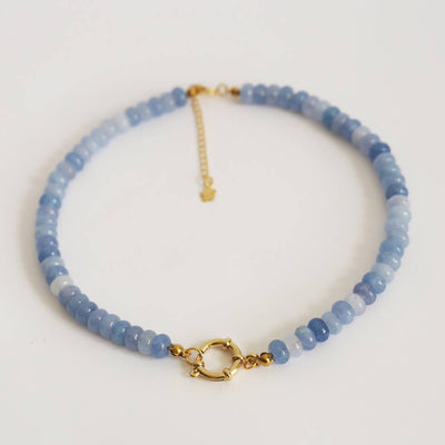Blue beaded necklace with gold clasp on a white background