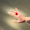Hand with a red ring on a neutral background