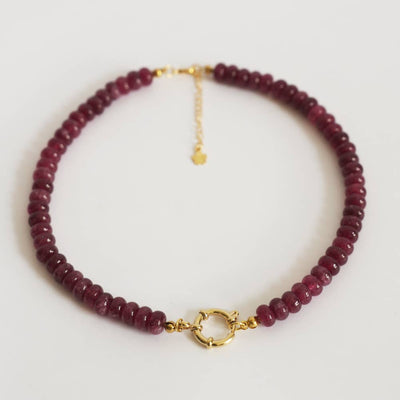 Beaded necklace with gold clasp on a light gray background