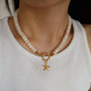 beaded necklace with a gold clasp and starfish charm worn by a person in a white top.