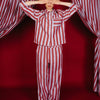 Person wearing red and white striped pajamas standing in front of red and white striped curtains.