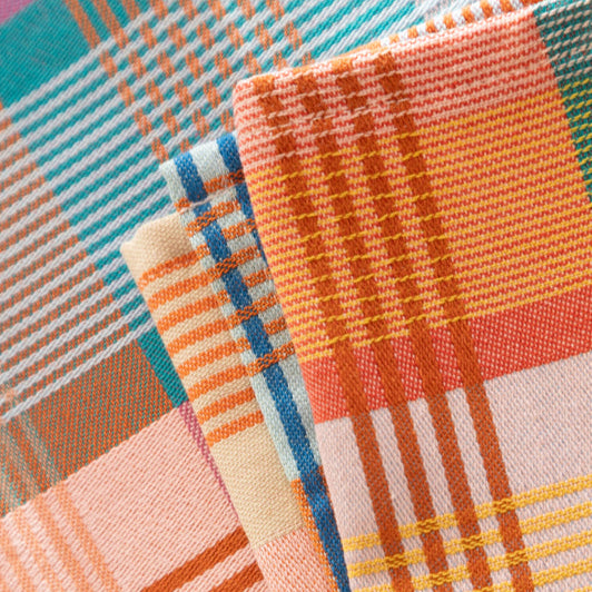 Close-up of colorful plaid fabric with orange, blue, and pink patterns.