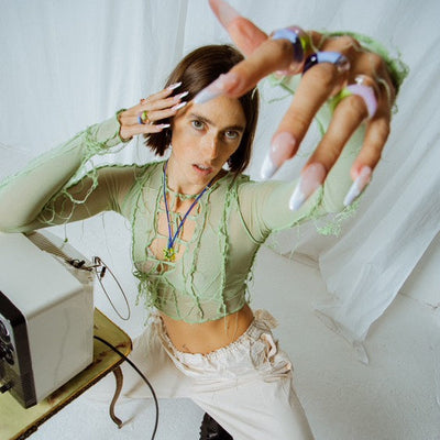 Person in a green top and white pants with a vintage computer setup.