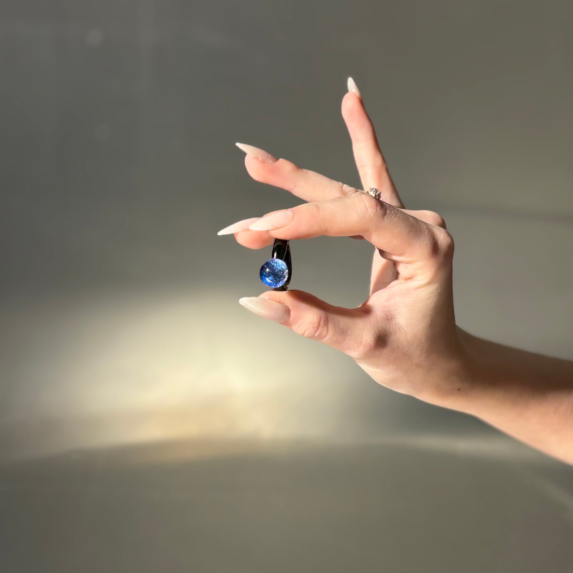 Hand holding a small blue object against a neutral background