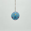 Decorative blue ball with floral patterns and a hook on a light gray background