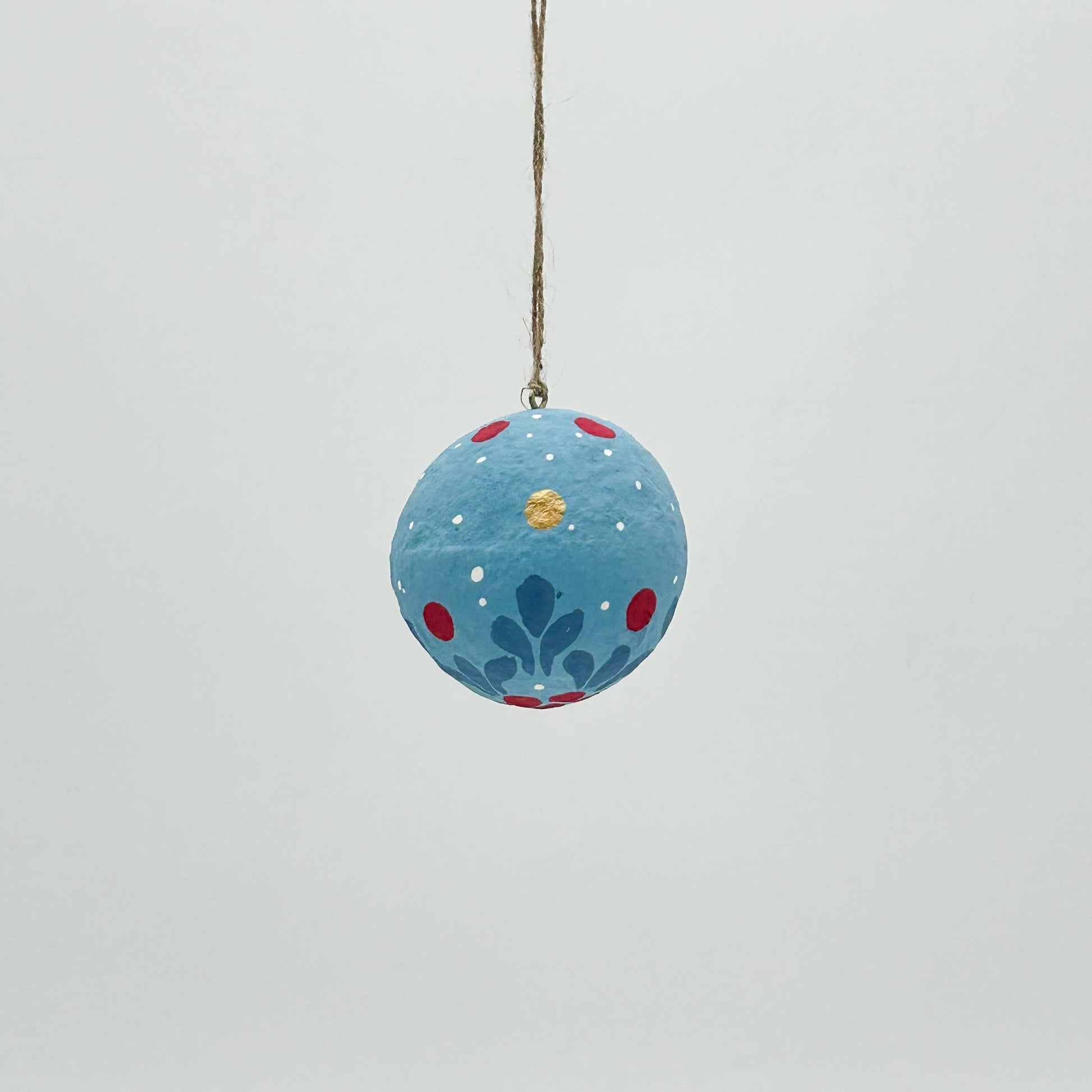 Decorative blue ball with floral patterns and a hook on a light gray background