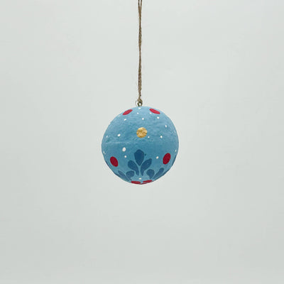Decorative blue ball with floral patterns and a hook on a light gray background