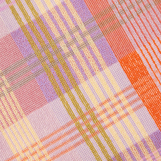 Close-up of a fabric with a plaid pattern in pink, orange, and yellow.