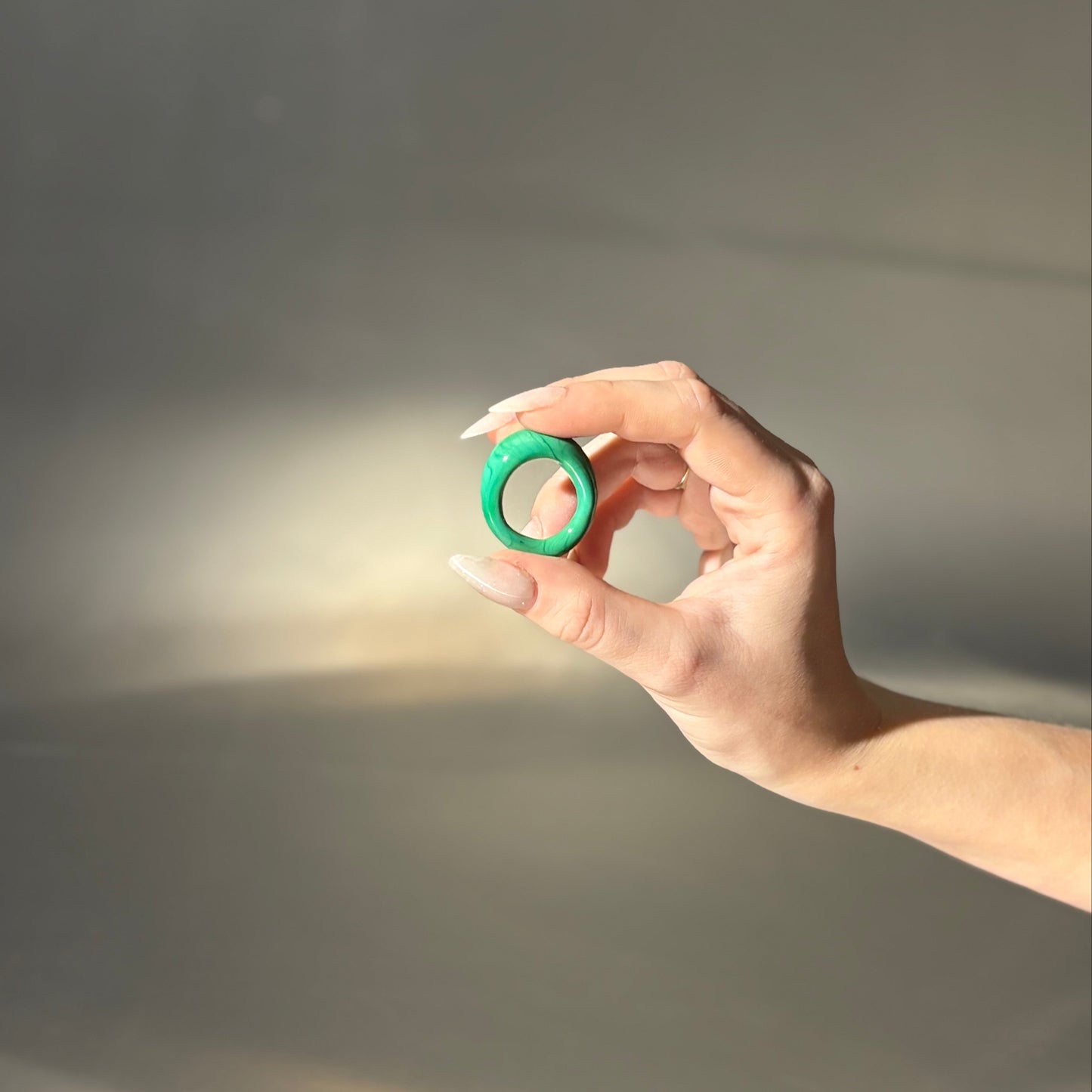 Hand holding a green object against a dark background