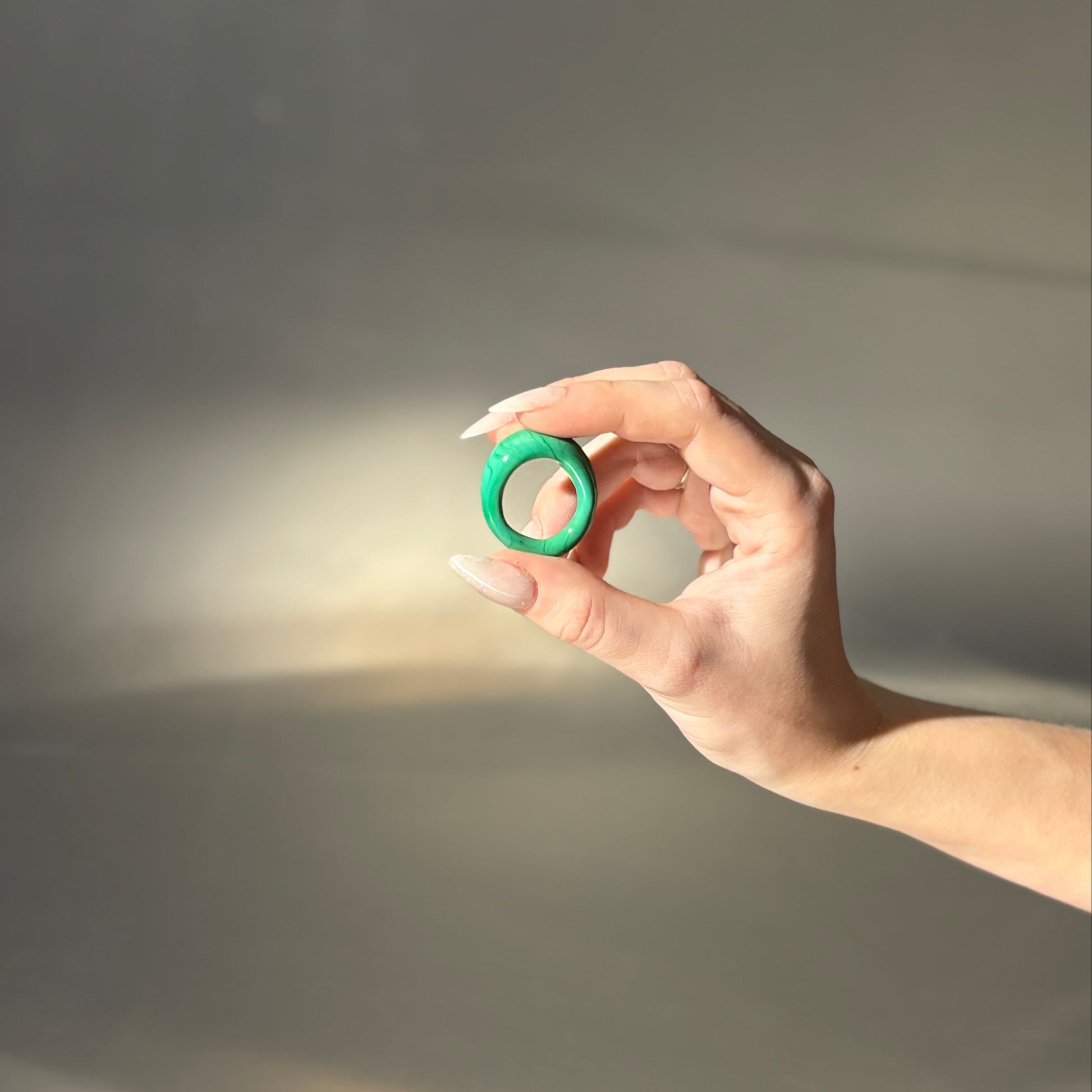 Hand holding a green object against a dark background