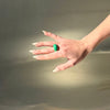 Hand with a green ring on a gray background