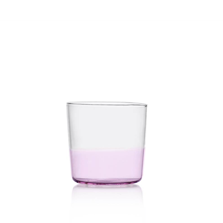 water glass with a pink bottom half, design by Alba Gallizia for Ichendorf Milano, photographed against a white background with a visible reflection on a flat white base