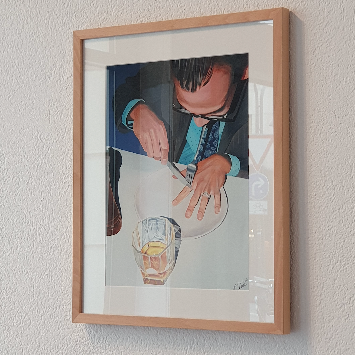 Framed picture of a person cutting a lemon on a white plate with a glass of water.