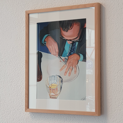 Framed picture of a person cutting a lemon on a white plate with a glass of water.