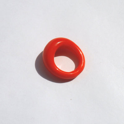 murano glas ring in vibrant bright coral red, in sunlight on a white background
