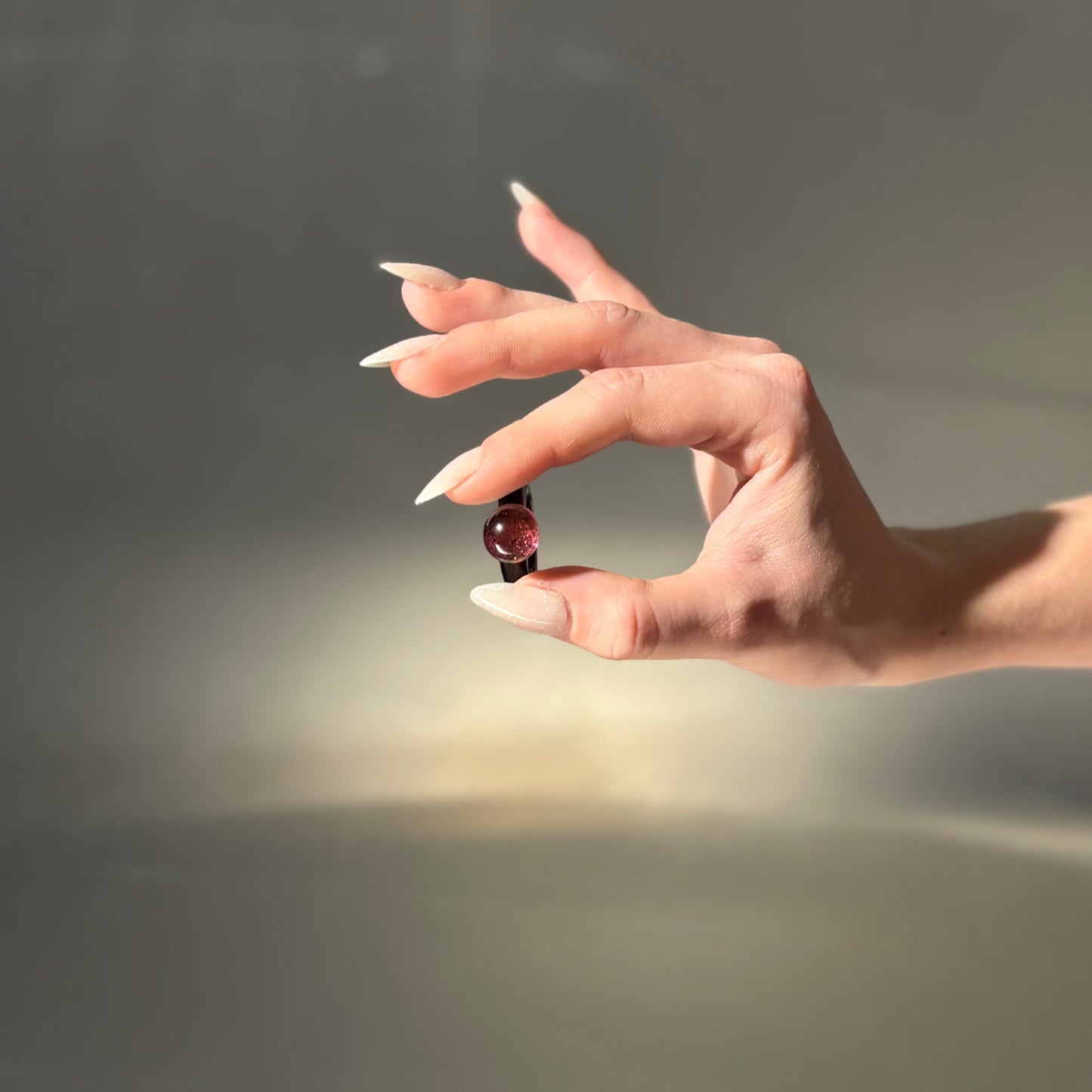 Hand holding a small object against a neutral background