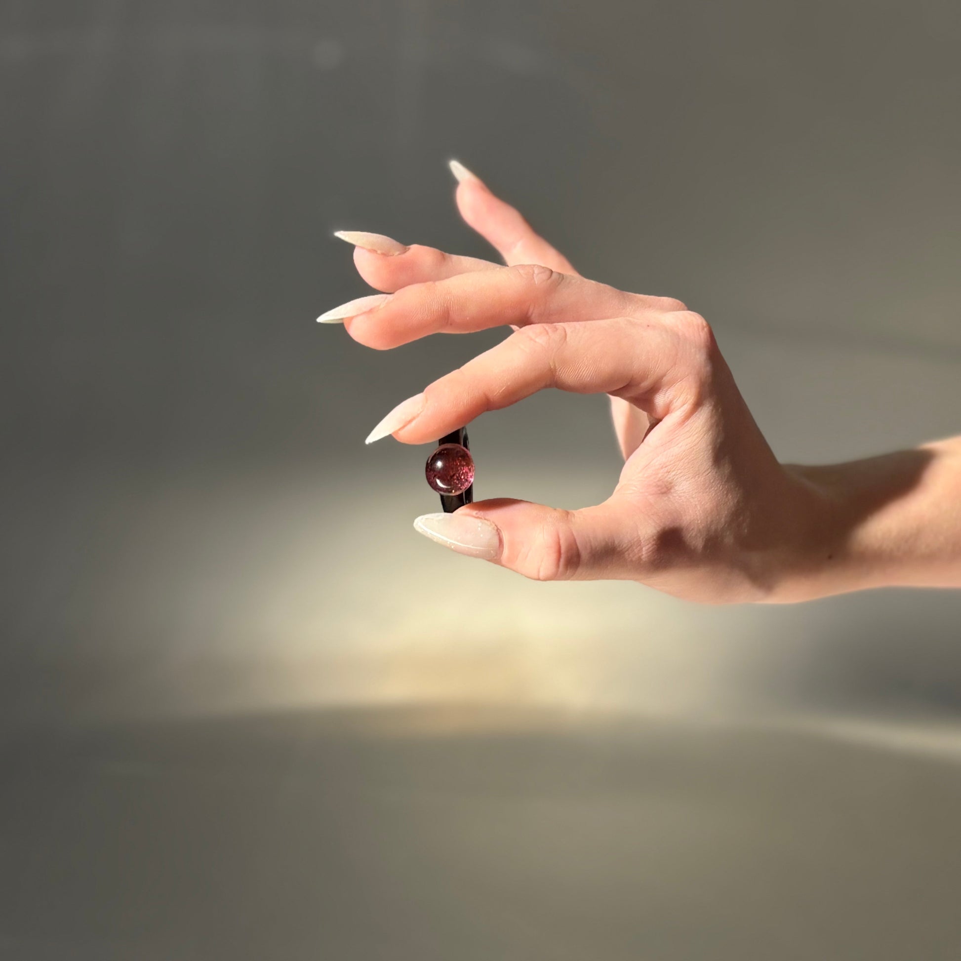 Hand holding a small object against a neutral background