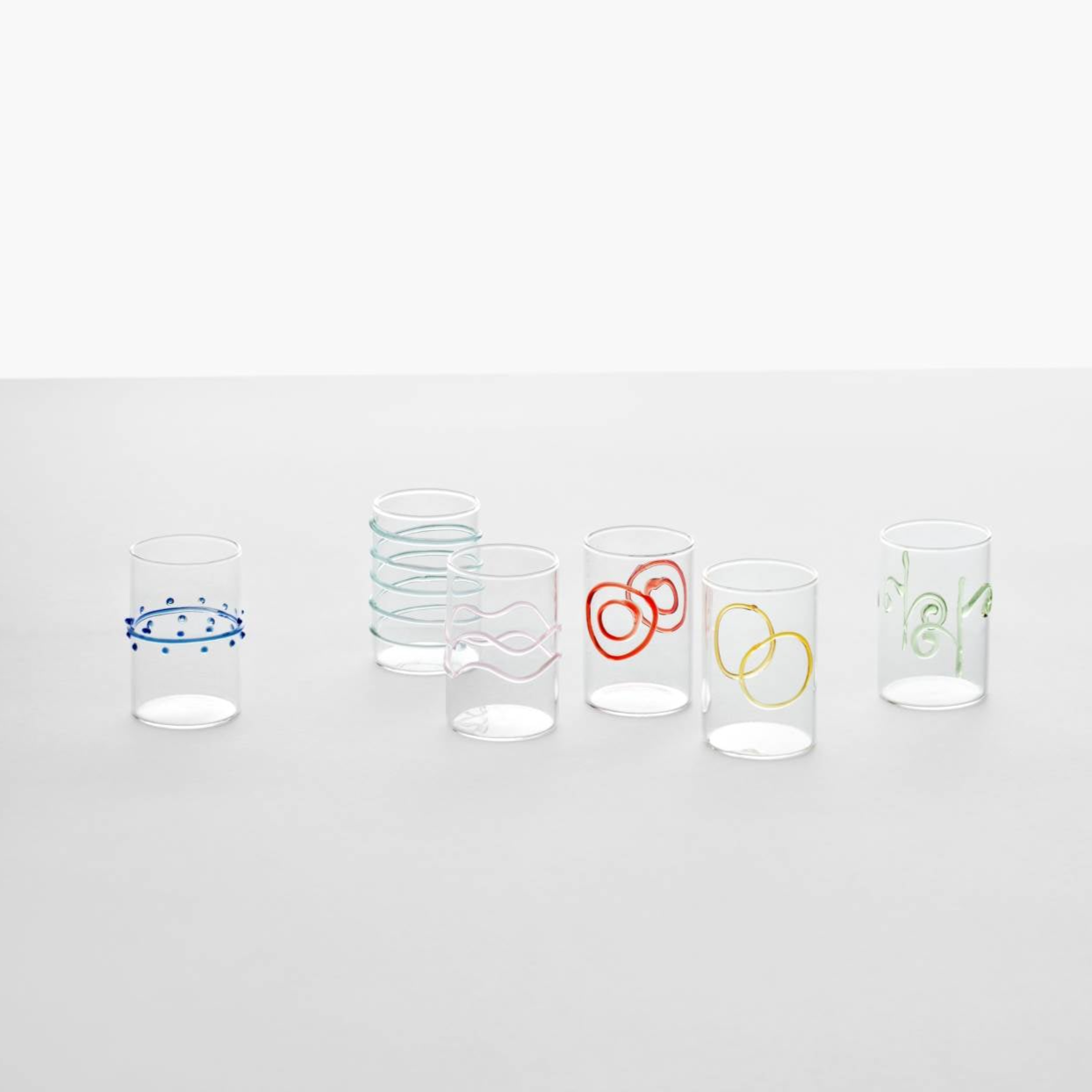 colourful set of 6 water glasses in the style of Decó arlecchino by design studio Forti E Di Loreto, photographed on a grey and white background