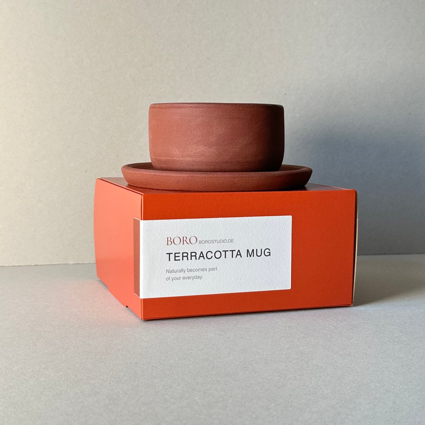 Terracotta mug with an orange box on a light gray background