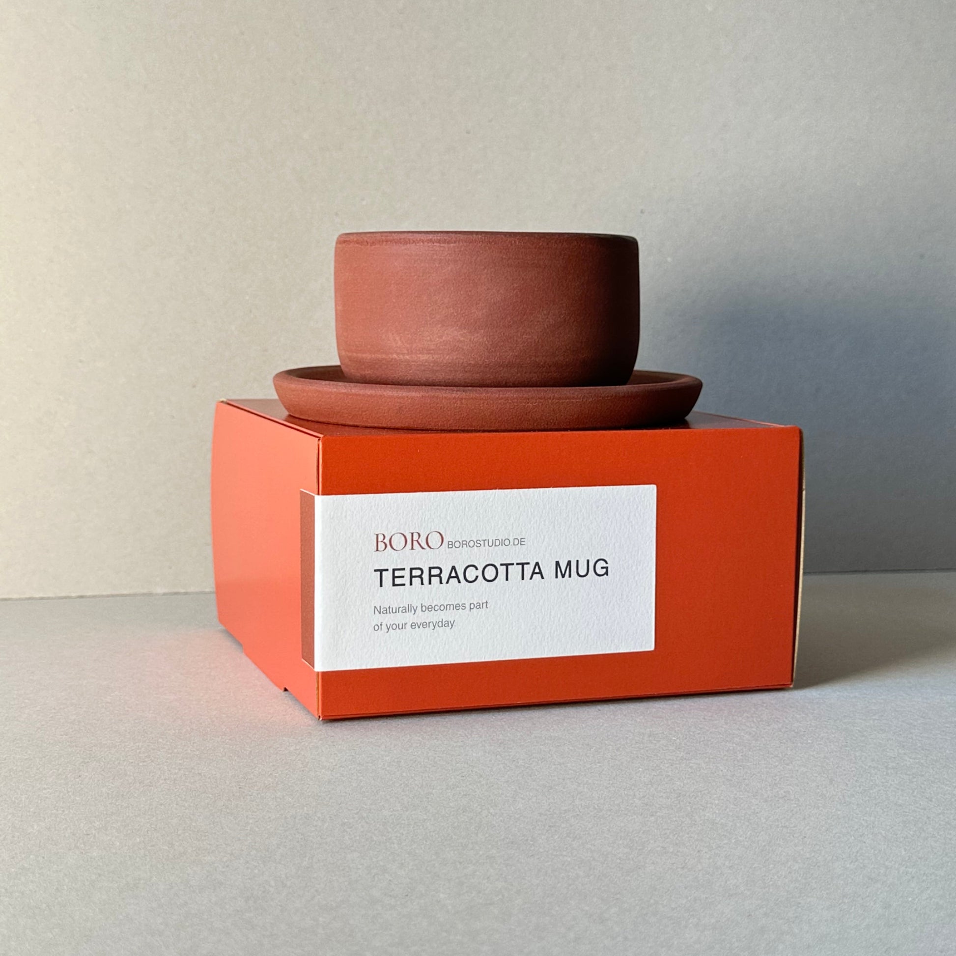Terracotta mug with an orange box on a light gray background