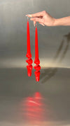 Red candlesticks held by a hand against a reflective gray background