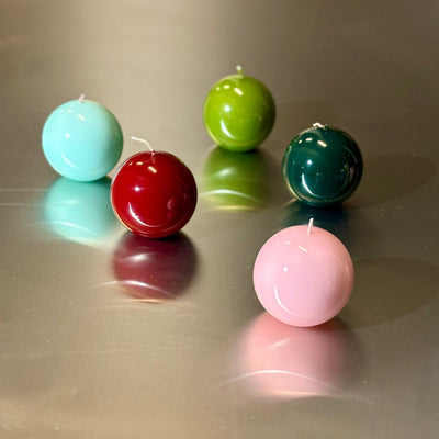 Five colorful spherical candles on a reflective surface