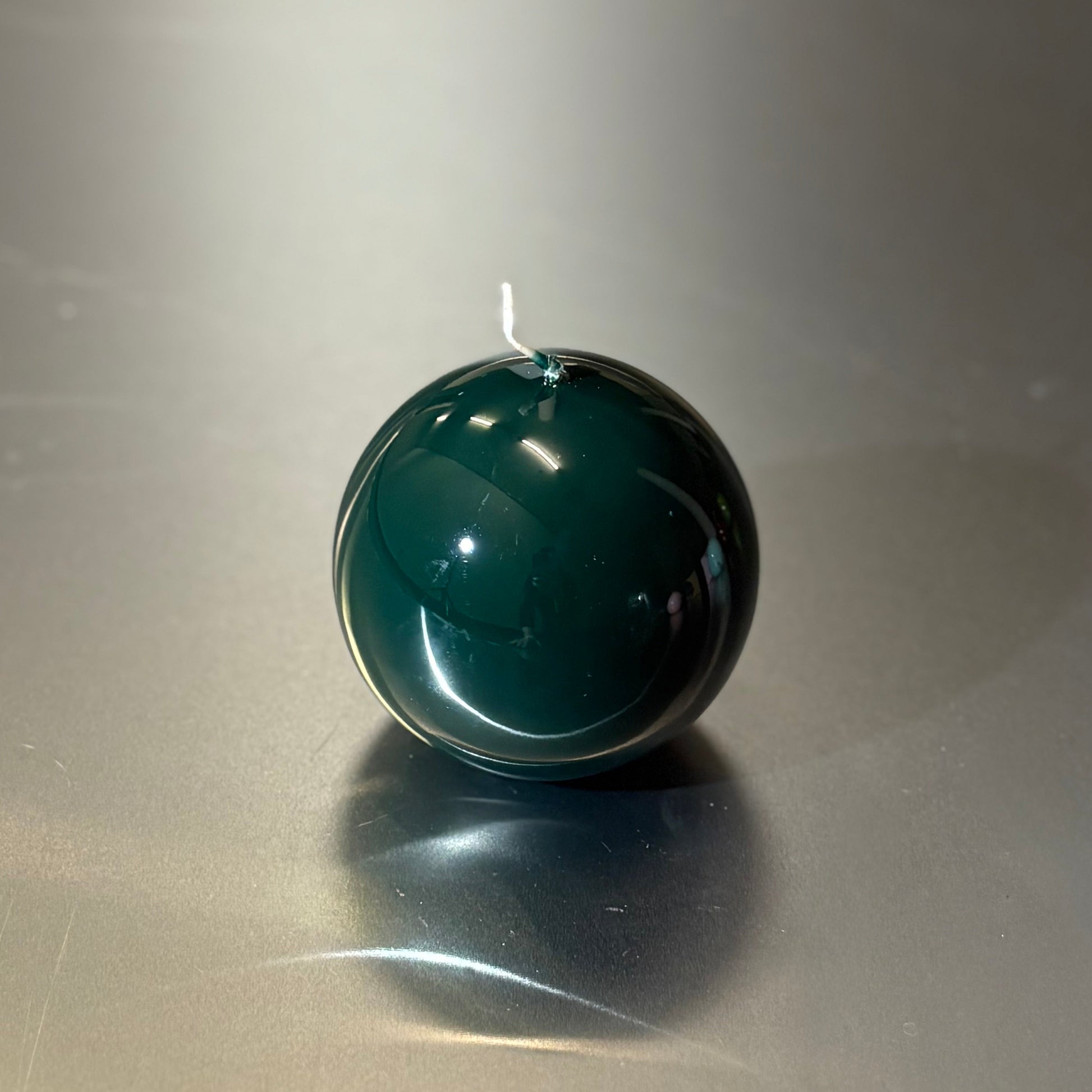 Green candle on a reflective surface