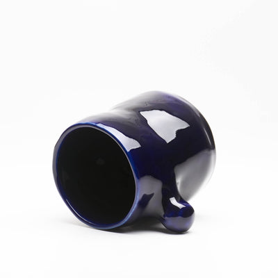 A hand-built ceramic mug in ocean blue glaze, featuring a knob-shaped handle reminiscent of underwater kelp leaves.