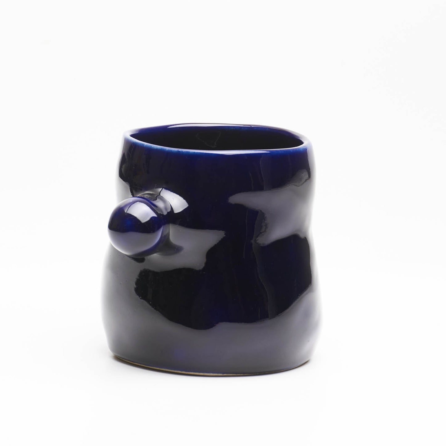 A hand-built ceramic mug in ocean blue glaze, featuring a knob-shaped handle reminiscent of underwater kelp leaves.