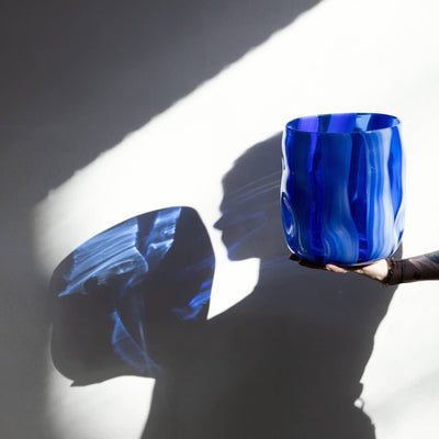 bright blue vase in hand, photographed in the sunlight, throwing a blue shadow