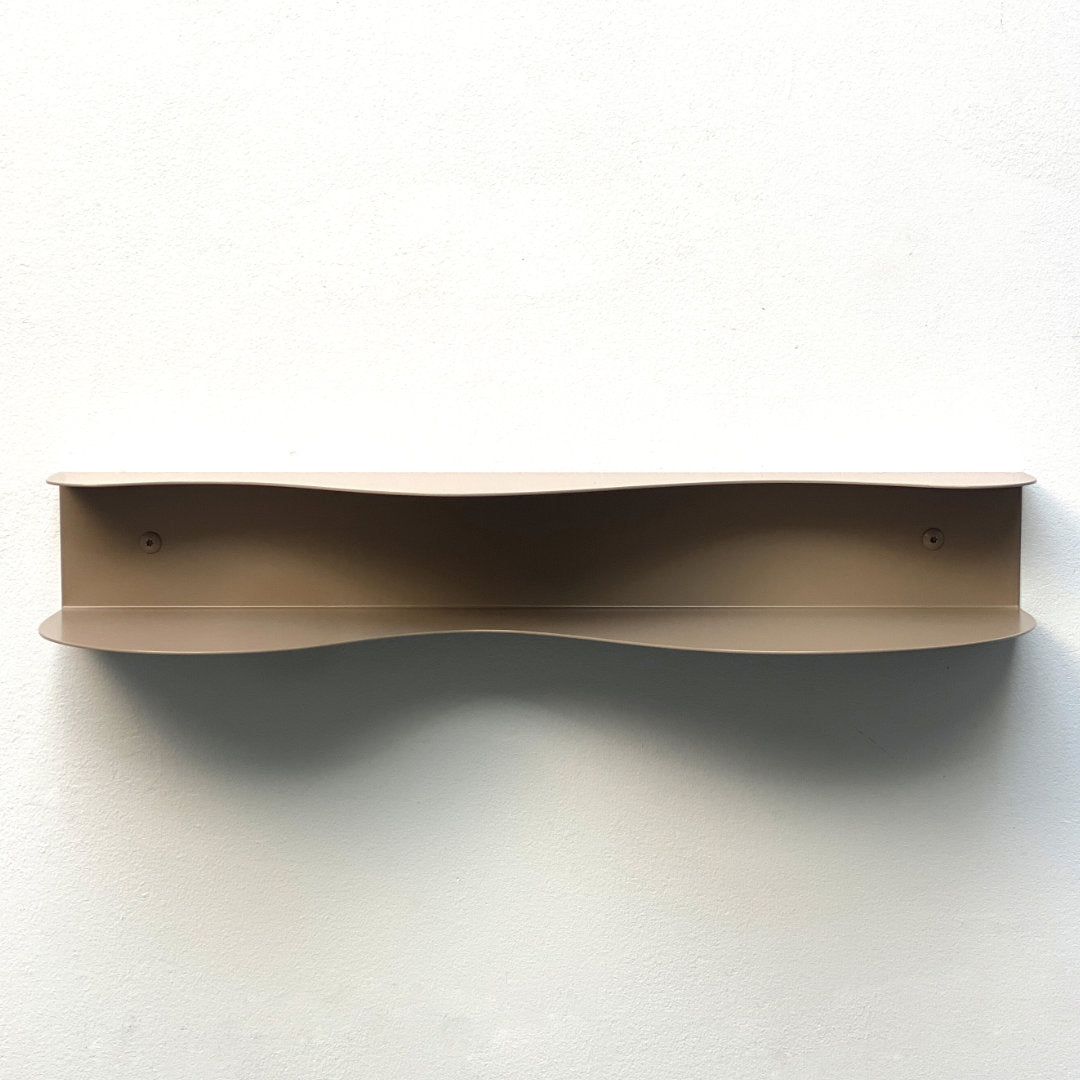 front of blob shaped curvy shelf in beige against a white wall