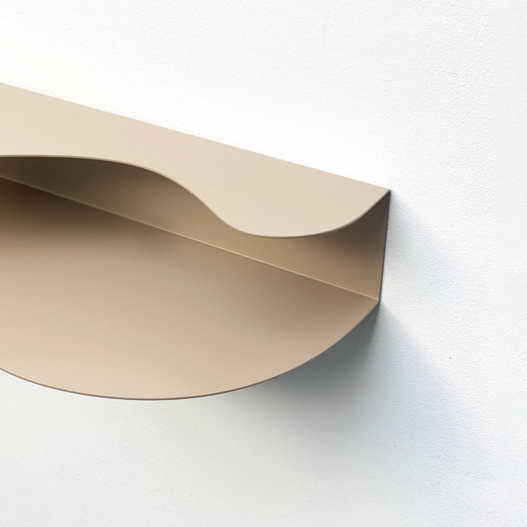 detail from above blob shaped curvy shelf in beige against a white wall