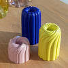 three different sized and coloured candle holders, all with a swirly design, similar to a bundting cake. in the shades rosy pink, lemony yellow and royal blue